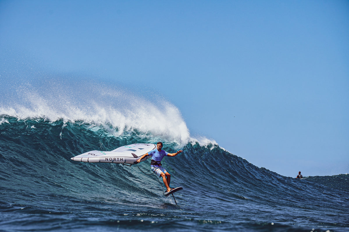 Person surfing on a wave with a clear blue sky
